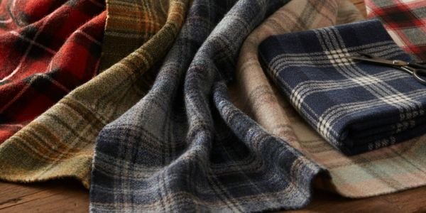 Καρό ύφασμα, μάλλινο, σε αποχρώσεις του κόκκινου, λευκού και μαύρου, διπλωμένο σε απαλές πτυχές.